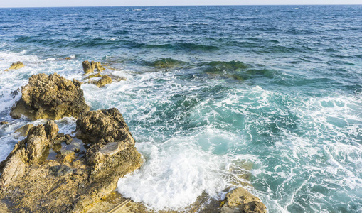 夏日悬崖旁的地中海, 强烈的波浪打破与岩石和留下蓝色和绿松石的颜色连同泡沫的海