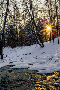 平静的冬天照片的一部分冰冻的河流与太阳照耀在相机, 使美丽的太阳星太阳耀斑