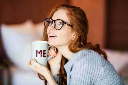 美丽的年轻红头发的女人摆着杯子