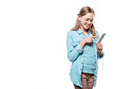 美丽的微笑的女孩在耳机使用智能手机隔离白色