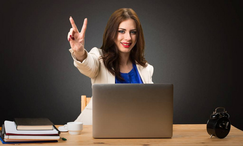 商务妇女与她的笔记本电脑, 并在黑色背景上取得胜利手势