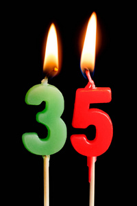 燃烧蜡烛的形式为35三十五数字 (数字, 日期) 的蛋糕孤立的黑色背景.