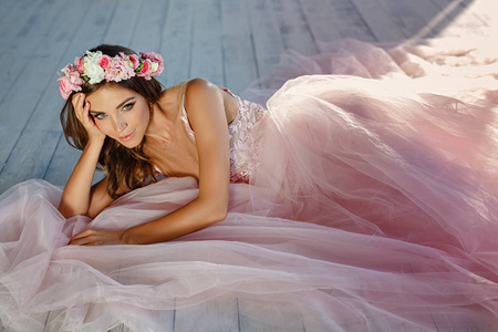 精致美丽的女孩在粉红色的礼服和花圈的花朵
