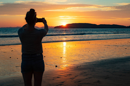 剪影女性游人在海滩期间拍摄海在太阳期间