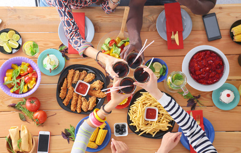 顶视图的一群人在一起时坐在木桌吃饭.在桌子上的食物.人们吃快餐照片