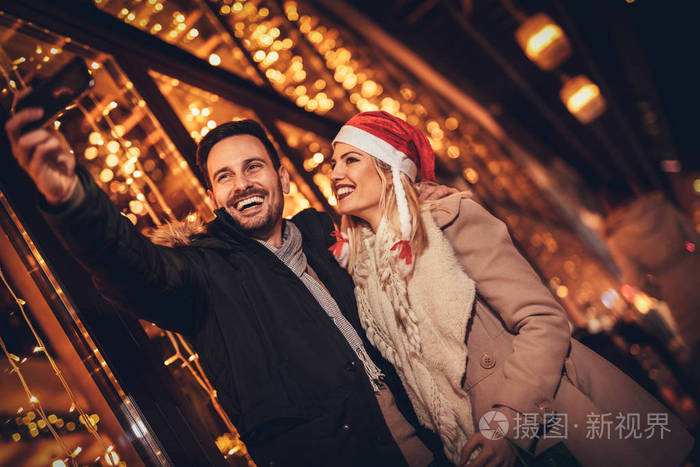 年轻欢快的夫妇采取自拍在城市街道在新年夜