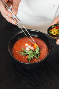 妇女烹调美味的西红柿汤与欧芹