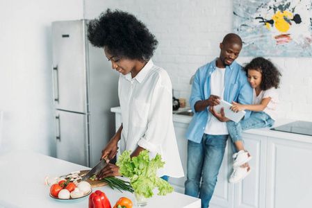 非洲裔美国人选择的焦点与家庭一起烹调早餐用片剂在柜台后面在厨房在家