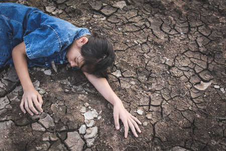 哀伤的女孩疲倦和用尽在破裂的干燥地面, 概念干旱和缺水危机