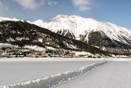 一个滑雪背道而驰和雪山和一个镇在阿尔卑斯瑞士冬天的看法