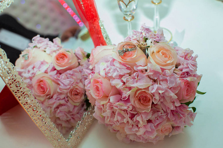 婚礼花束粉红色玫瑰和结婚戒指在一个木桌上。复制空间。婚礼聚会爱情家庭和戒指的概念