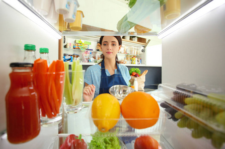 女性站附近打开冰箱充分的健康食品，蔬菜和水果的画像。女性肖像