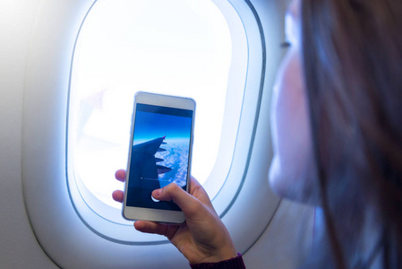 年轻女子使用手机智能手机, 拍照在飞机上