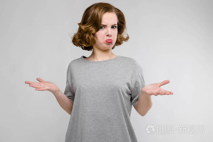 美丽的红发女孩的肖像愁眉苦脸的灰色背景