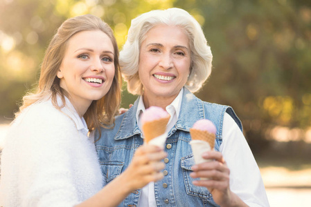 快乐的年轻妇女享受冰淇淋与老母亲户外