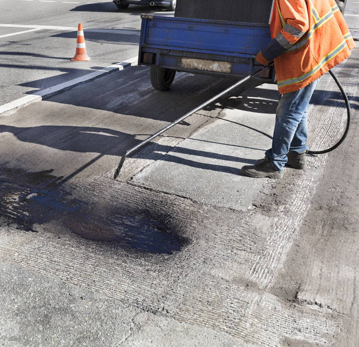 沥青路面部分修复工人在沥青表面喷洒沥青