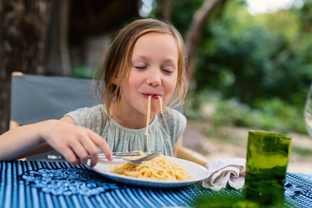 可爱的小女孩在餐厅午餐吃意大利面条的肖像