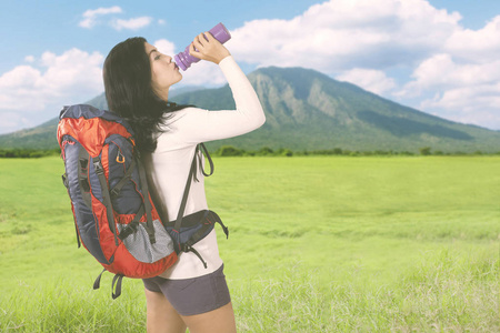 美丽的徒步旅行妇女在山里喝