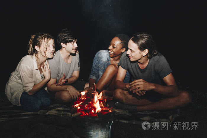 一群年轻的成人朋友围坐在篝火旁户外休闲和友情概念