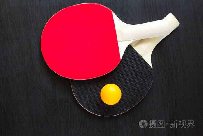 黑色背景下的两个乒乓球或乒乓球拍和球