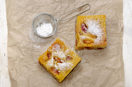 水果蛋糕油桃 厨房用纸 筛，木制的桌子上糖粉