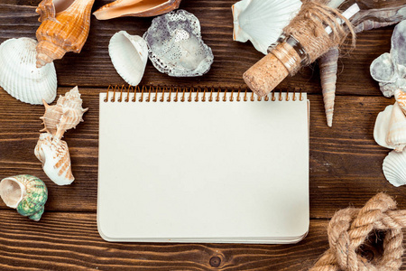 木桌上的贝壳和记事本.具有复制空间的顶部视图照片