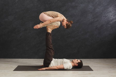 年轻夫妇在垫子上练习 acroyoga