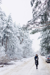 女孩走在一条积雪的森林小路中间。