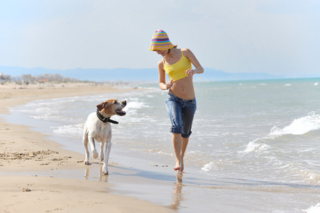 年轻女子在沙滩上玩她的狗