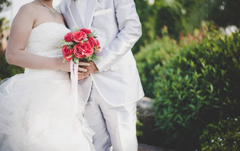 新娘举行婚礼红玫瑰花束在手, 新郎拥抱