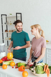 夫妇的素食者在厨房做饭的时候微笑着聊天