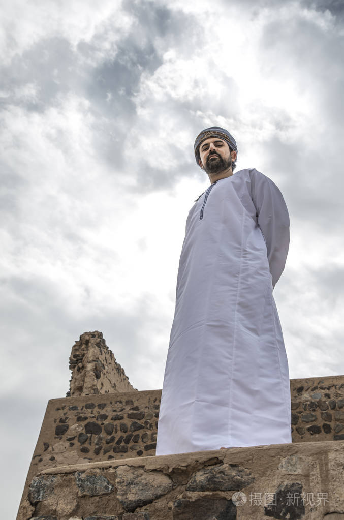 阿拉伯人在传统阿曼服装站立反对多云天空背景