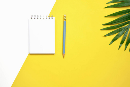 白色屏幕笔记书空白和笔放置在柔和的黄色背景。适用于用于广告的图形