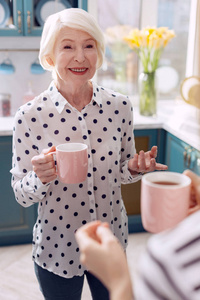 老妇人喝咖啡在厨房和谈话