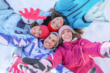 一群快乐的朋友躺在雪地上