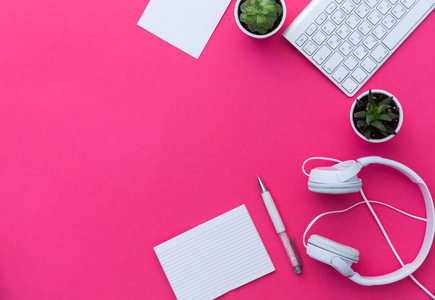 创意女性桌面, 白色平板电脑和耳机与空白复制空间屏幕的顶级视图。模拟, 平躺, 粉红色粉彩背景