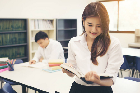 年轻的亚洲学生在图书馆读一本书。教育理念