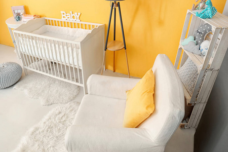 儿童房内带婴儿床和舒适的扶手椅