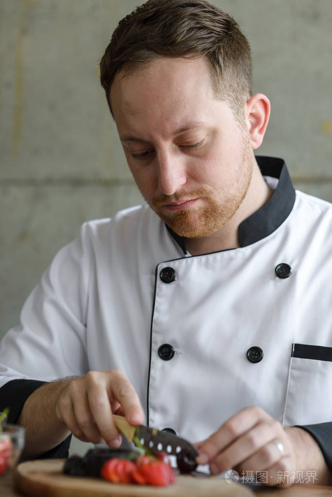 装饰甜点在厨房里一个集中的男性西点厨师的特写照片-正版商用图片04c