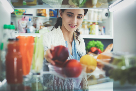 女性站附近打开冰箱充分的健康食品，蔬菜和水果的肖像