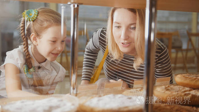 女孩与辫子和她的妈妈看在馅饼在窗口选择