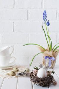 复活节春天的装饰组成与白色的鸡蛋在一个巢与花。节日装饰品。复活节节日餐桌设置