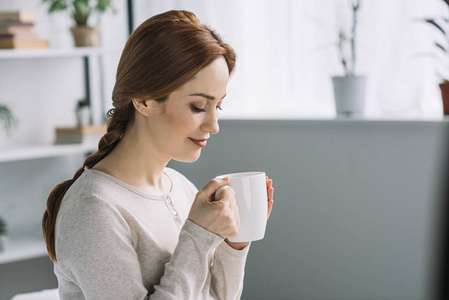 美丽的孕妇在家里喝茶的侧面视图穿着浴衣喝茶的女人家庭母亲和孩子