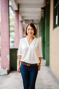 一位亚洲华人女经理的肖像在白天站着。她在白天站在走廊里, 自信地微笑着。