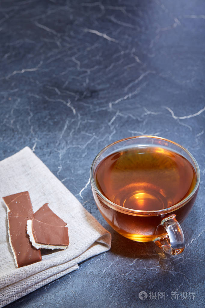 在深灰色的大理石背景上一杯红茶与巧克力片的垂直图片顶部视图