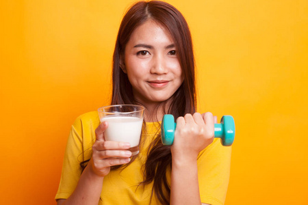 健康亚洲妇女喝一杯牛奶和哑铃在 yel