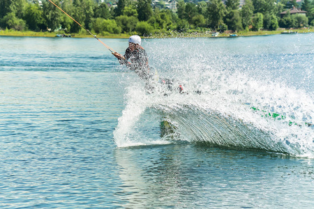 wakeboarder 从一个跳板后面跳下一根绳子, 在水面上发出波浪。