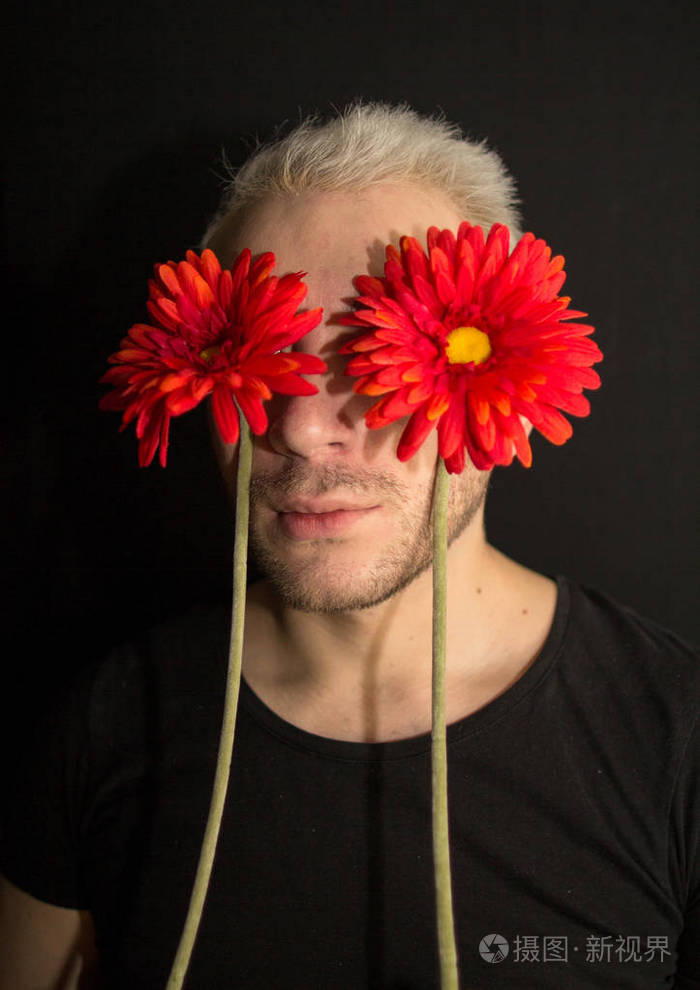 一个年轻胡子男子的肖像他的眼睛上有红色的花朵黑人背景的男人