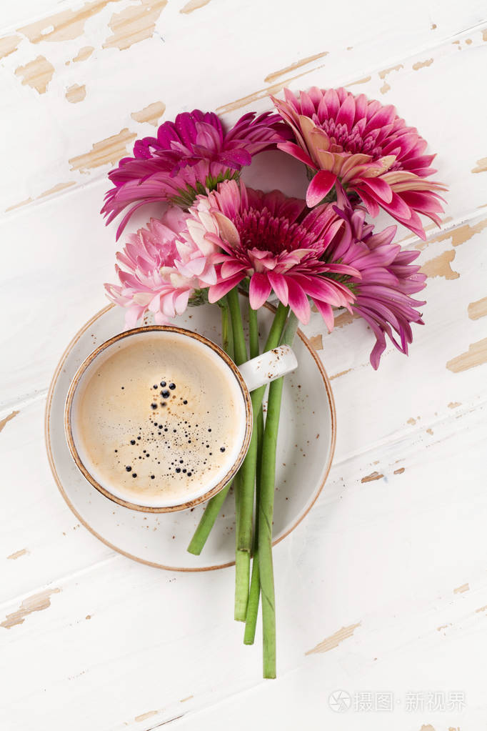 咖啡杯和非洲菊花花束在白色木桌上顶部视图