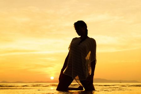 夕阳下海滩上一个年轻而健康的女人的剪影